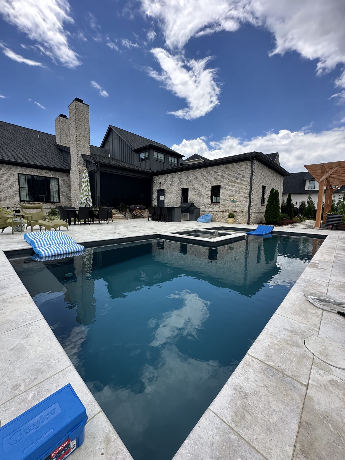 Pool and attached spa behind a brick home, serviced by Bright Water