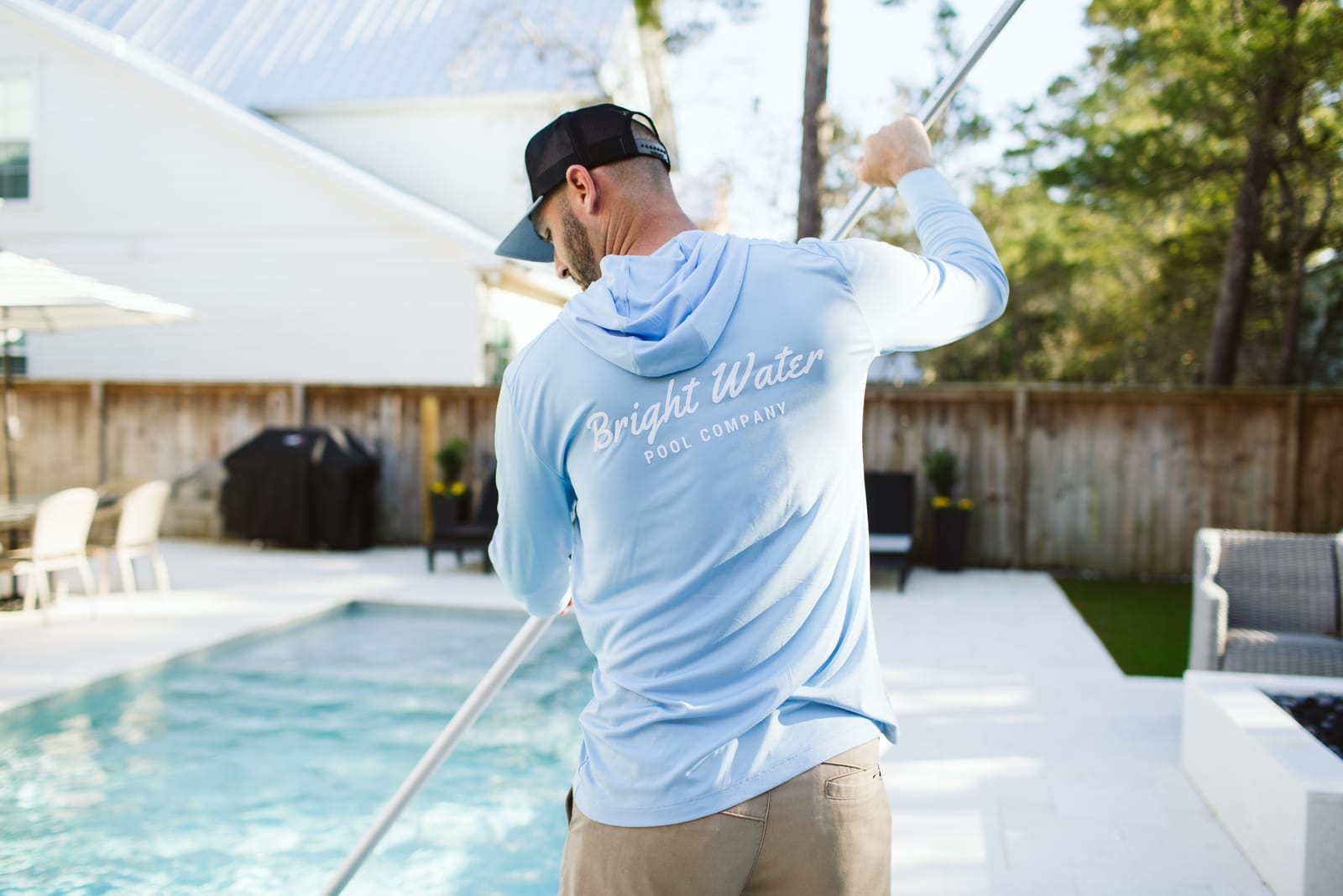Bright Water Pool Company technician skimming a residential pool